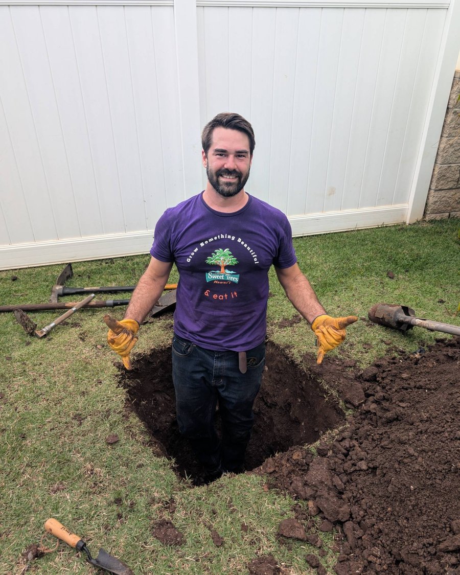 Sage of Sweet Trees Hawaii standing in a planting hole he dug by hand