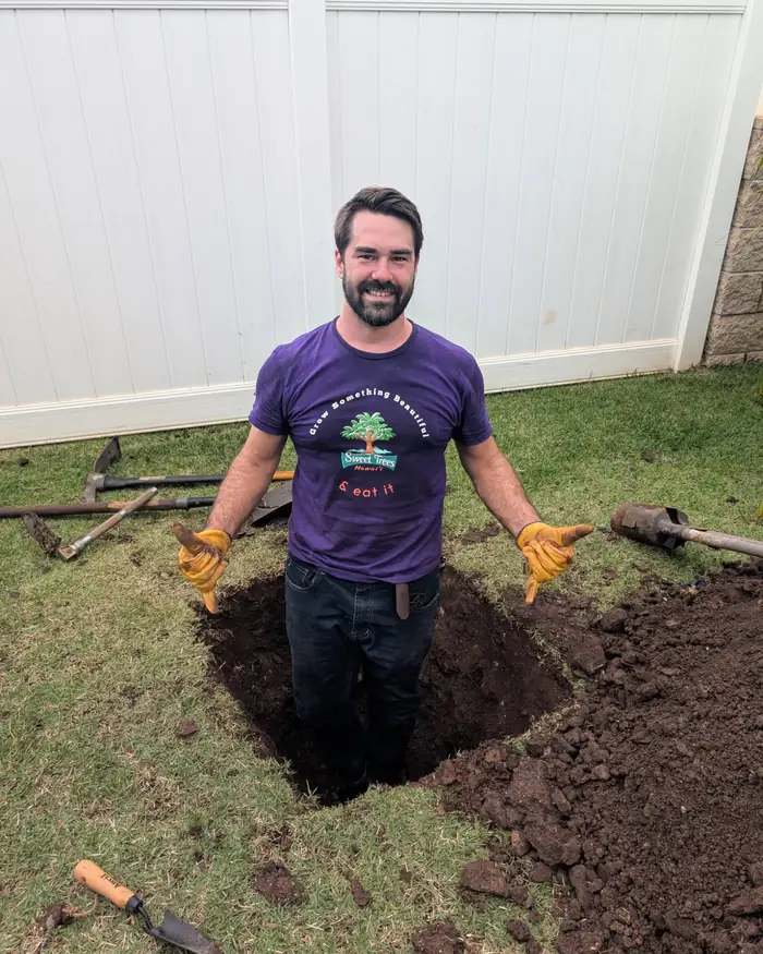 Sage of Sweet Trees Hawaii standing in a planting hole he dug by hand